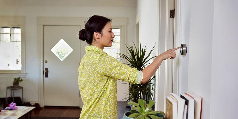Homeowner adjusting thermostat